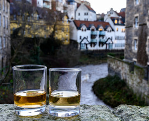 Scotch single malts or blended whisky spirits in glasses with old houses of Edinburgh on background, Scotland, UK
