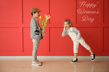 Cute boy giving bouquet to little girl on color background. International Women's Day celebration