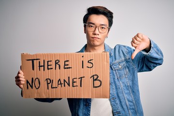 Young handsome chinese activist man protesting asking for care the planet on manifestation with angry face, negative sign showing dislike with thumbs down, rejection concept