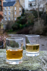 Scotch single malts or blended whisky spirits in glasses with old houses of Edinburgh on background, Scotland, UK