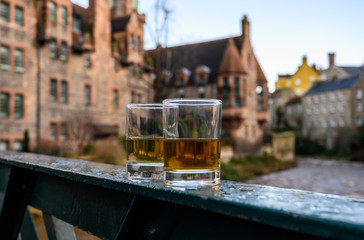 Scotch single malts or blended whisky spirits in glasses with old houses of Edinburgh on background, Scotland, UK