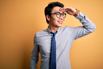 Young handsome chinese businessman wearing glasses and tie over yellow background very happy and...