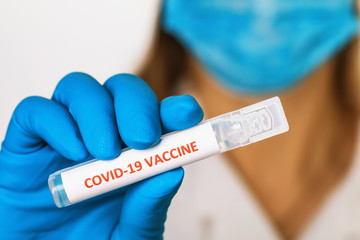 Fototapeta premium Doctor holds in his hand an ampoule with a vaccine against coronavirus COVID-19, close-up