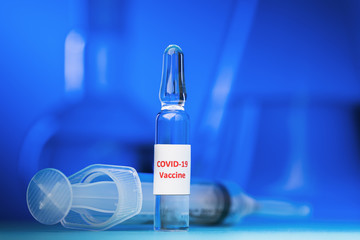 COVID-19 coronavirus vaccine ampoule on blue background, close-up
