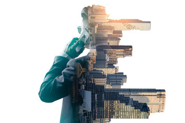 The double exposure image of the businessman standing back during sunrise overlay with cityscape image. The concept of modern life, business, city life and internet of things.