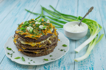 Liver pie with stewed carrots, onions and dill on a blue wooden background close-up. Cold meat appetizer with vegetables for dinner.