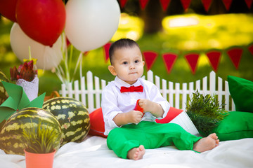 Fototapeta na wymiar Laughing baby boy 1-2 year old eating watermelon outdoors. Summer party concept