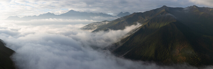 An unidentified woman wearing red jacket standing on a mountain peak above the clouds