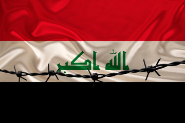 iron barbed wire against the background of the national silk flag of the state of Iraq, the concept of imprisonment for offenders, for the siege area