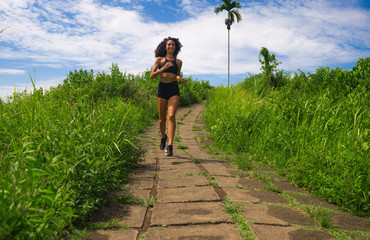 Fototapeta na wymiar happy female runner training on countryside road - young attractive and fit jogger woman doing running workout outdoors at beautiful track in healthy lifestyle and sport