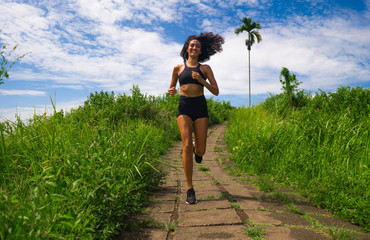happy female runner training on countryside road - young attractive and fit jogger woman doing...