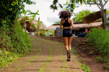 rear view female runner training on countryside road - young attractive and fit jogger woman doing...