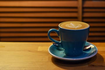 Coffee in blue cup on wooden table with copy space.