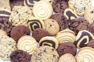 A group of assorted cookies. Chocolate chip, oatmeal, raisin, Danish cookies and biscuits in the shape of a spiral pattern close-up full frame background.