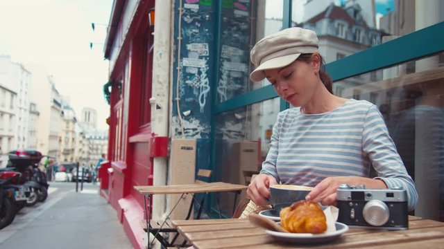 Young attractive girl having breakfast in a cafe in Paris