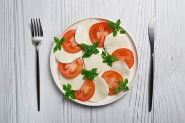 Salad caprese on white plate on light wooden table. Close up. 