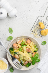 Pasta fusilli with salmon, broccoli, parmesan and basil in a creamy sauce in a plate on a light background. Healthy food. Space for text. Top view