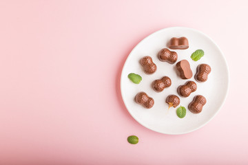 Chocolate caramel candies on a pastel pink background. top view, copy space