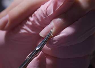 A manicurist cuts off the cuticle of nails with scissors. Cuticle removal with nail scissors. Professional manicure in the salon close-up. - obrazy, fototapety, plakaty