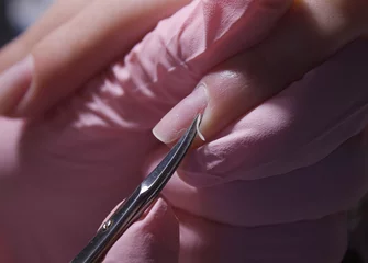  A manicurist cuts off the cuticle of nails with scissors. Cuticle removal with nail scissors. Professional manicure in the salon close-up. © OleJohny