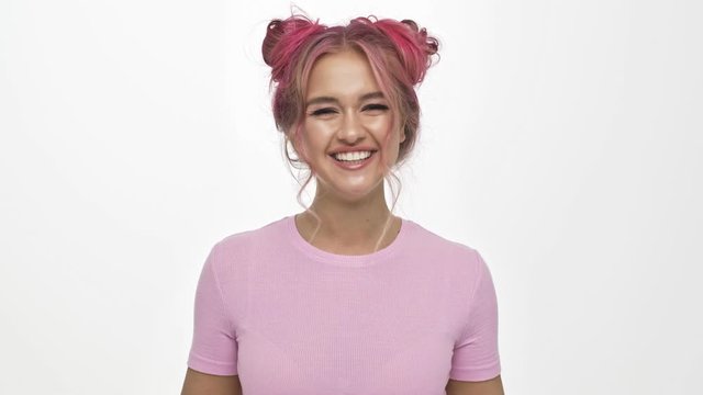A smiling young woman with the colored pink hairstyle is rejoicing isolated over white background