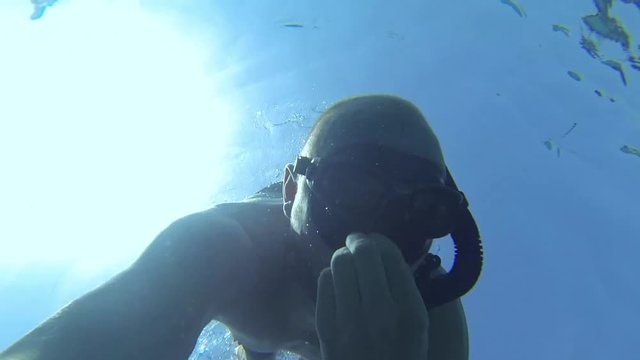 Male freediver equalizing the pressure on his ears while descending to the bottom of the Mediterranean Sea during dive on Mallorca, Spain.