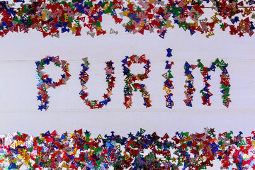 Confetti word Purim on white background.