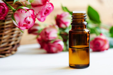 Small glass bottle with essential rose oil. Aromatherapy, spa and herbal medicine ingredients. Copy space.