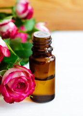 Small glass bottle with essential rose oil. Aromatherapy, spa and herbal medicine ingredients. Copy space.
