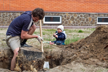happy gardener dad uproots an old stump from the ground with a little son