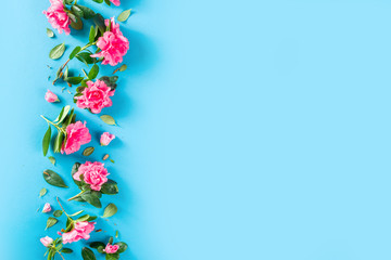 Floral pattern made of pink spring flowers, green leaves, branches on turquoise, aquamarine  background. Flat lay, top view. Spring holiday background