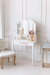 beautiful white interior. classic room with wooden floor light walls with moldings, chair dressing table with mirror, decorated with decor golden chandelier, lanterns
