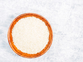 Indian long grain Basmati rice in brown wooden bamboo bowl on white concrete background. Indian cuisine, ayurveda, naturopathy concept