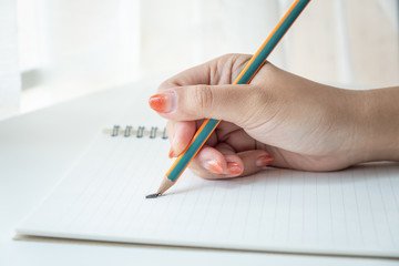 Female's hand holding a broken pencil on a notebook, stressful and unsuccessful concept