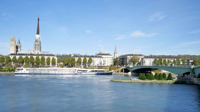 Cityscape of Rouen, a french city located in Normandy. View on the Seine river. In the background, there is the gothic cathedral, a famous monument of the city. Blue sky, day light, time lapse.