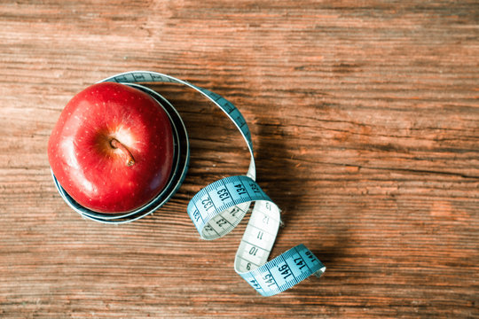 Isolated Red Apple Wrapped With Tape Measuring On White Background. Diet And Healthy Living Concept.