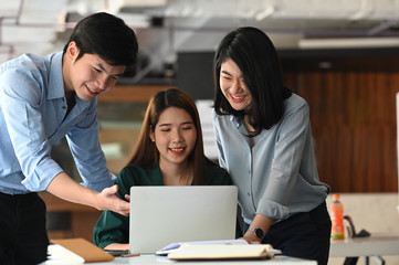 Business development team discussing/brainstorming/talking/meeting about them new business project while sitting/standing at the modern meeting table with meeting room as background.