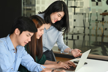 Business development team discussing/brainstorming/talking/meeting about them new business project while sitting/standing at the modern meeting table with meeting room as background.