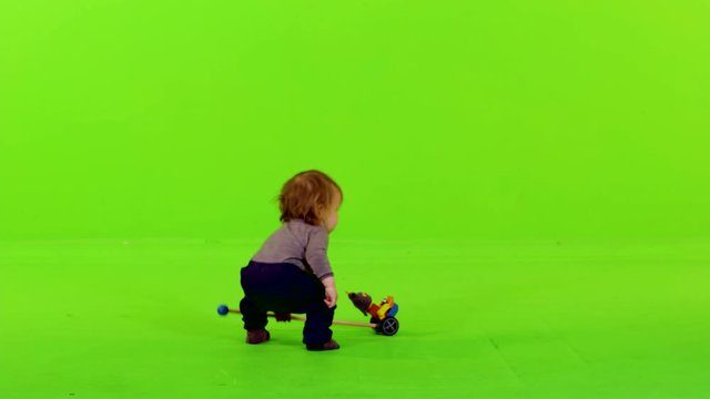 Cute little toddler playing with a toy over green screen.