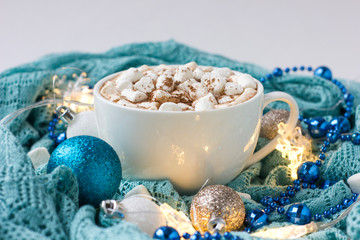 Christmas or New Year background with white cup of hot cocoa with marshmallows on blue background.