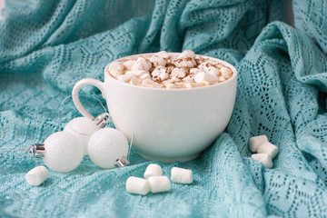 Christmas or New Year background with white cup of hot cocoa with marshmallows on blue background.