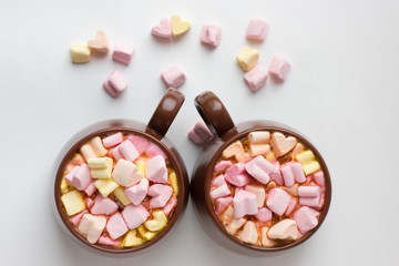 Obraz na płótnie Canvas Top view of brown cups of hot cocoa with marshmallows in heart shape on white background.