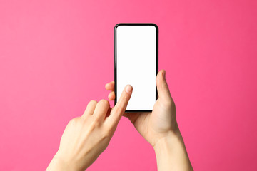 Female hands hold phone on pink background. Empty screen