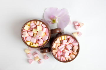 Obraz na płótnie Canvas Top view of brown cups of hot cocoa with marshmallows in heart shape on white background.