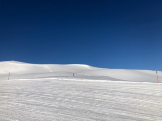 Empty snowy skiing slope in the mountains with blue sky