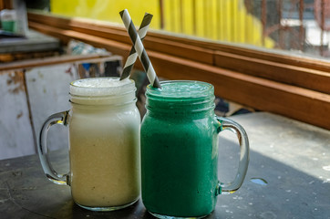 Banana smoothie and spirulina smoothie on a table in a cafe on a summer day. Bali drinks. Healthy lifestyle