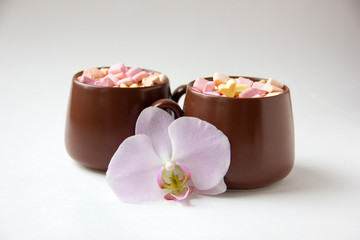 Brown cups of hot cocoa with marshmallows in heart shape on white background.