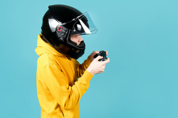 Obraz na płótnie Canvas side view of a teenager in a motorcycle helmet with a joystick from a game console