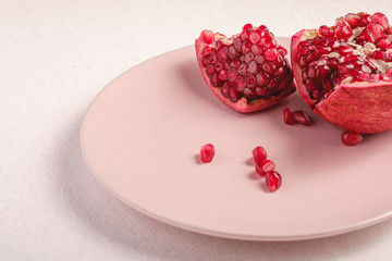 Fresh tasty sweet peeled pomegranate with red seeds in pink plate on white background, angle view,...