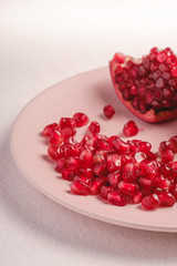 Fresh tasty sweet peeled pomegranate with red seeds in pink plate on white background, angle view, healthy food fruits